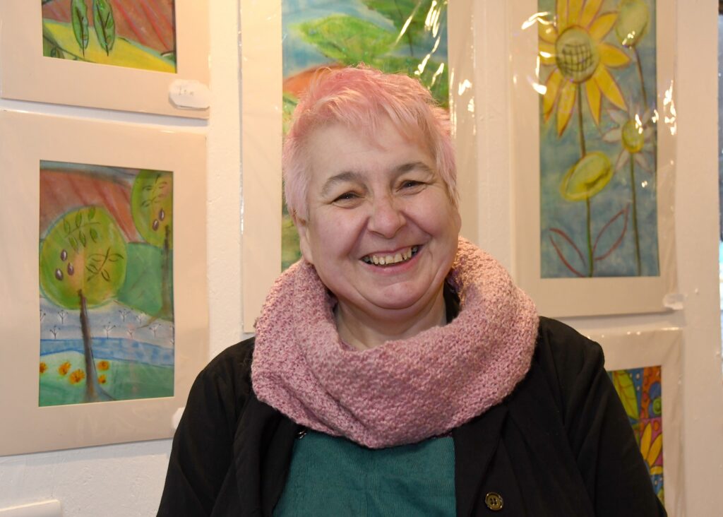 Mary smiling in front of some of her paintings