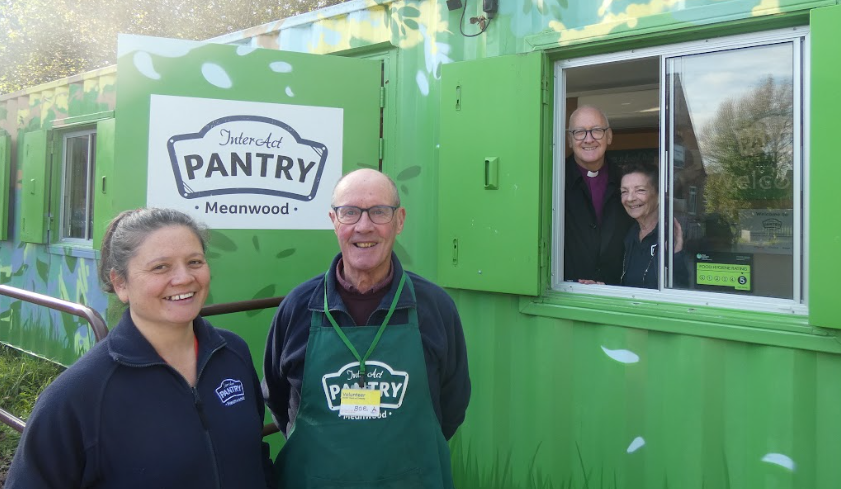 The Rt Revd Nick Baines, Bishop of Leeds, looks out of the InterAct Pantry window, with volunteers in the foreground