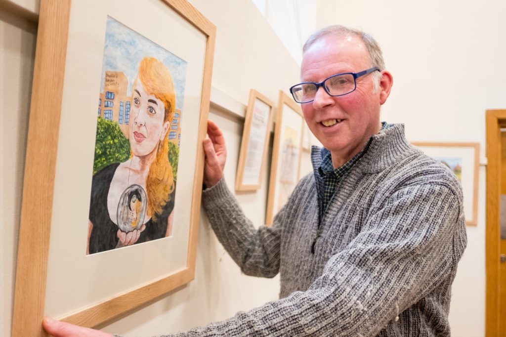 Stephen hods a wooden picture frame, containing a portrait of a woman (Liudmyla)