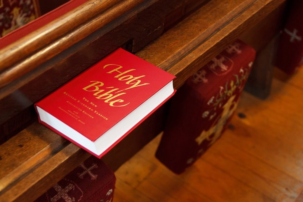 A red Holy Bible, on a wooden church pew