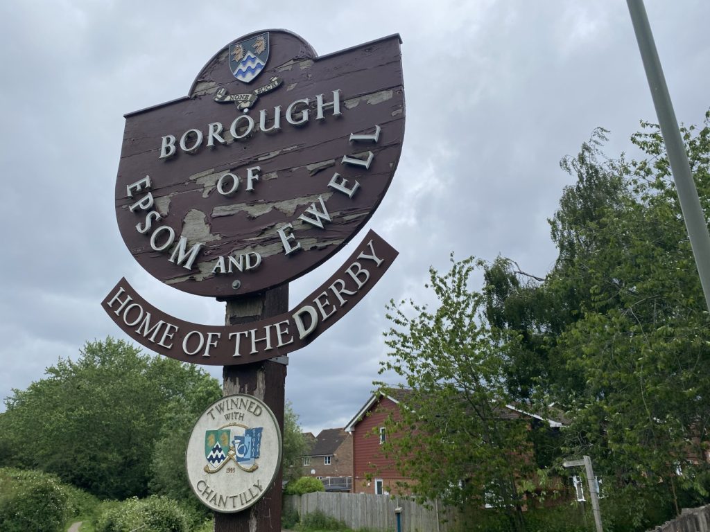 A street signpost reading: Borough of Epsom and Ewell, Home Of The Derby