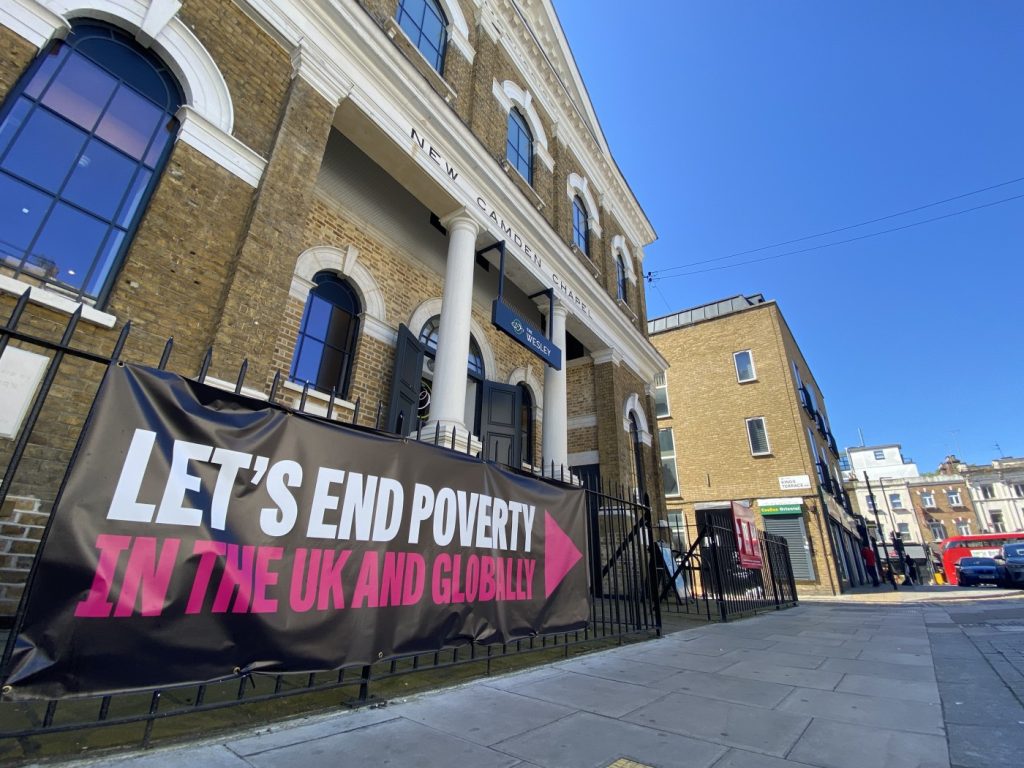 A "Let's End Poverty" banner on Camden Town Methodist Church