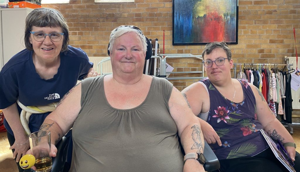 Three volunteers sitting for a posed photograph, inside the church hall