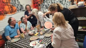 People sit around a table, as part of a plate-making art project