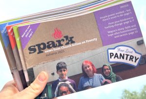 A hand holding a bundle of Spark newsletters