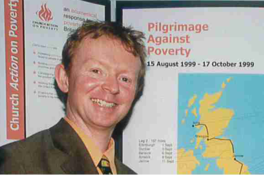 Niall in front of a Pilgrimage Against Poverty banner